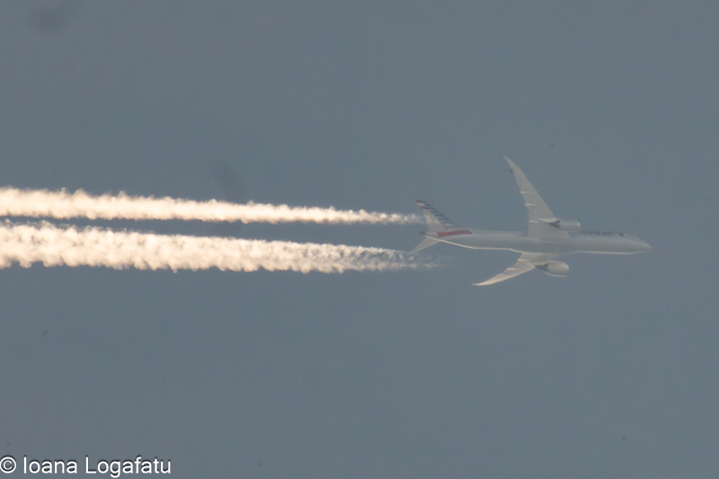 Clouds dance with a soaring airplane trail